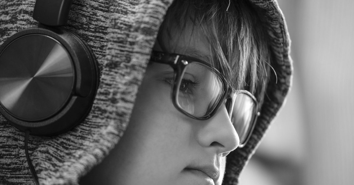 深夜书房里戴着耳机的听众闭眼聆听有声小说，窗外城市灯火与雨丝映在玻璃上，桌上一盏暖黄台灯照着手边的书页，氛围安静专注